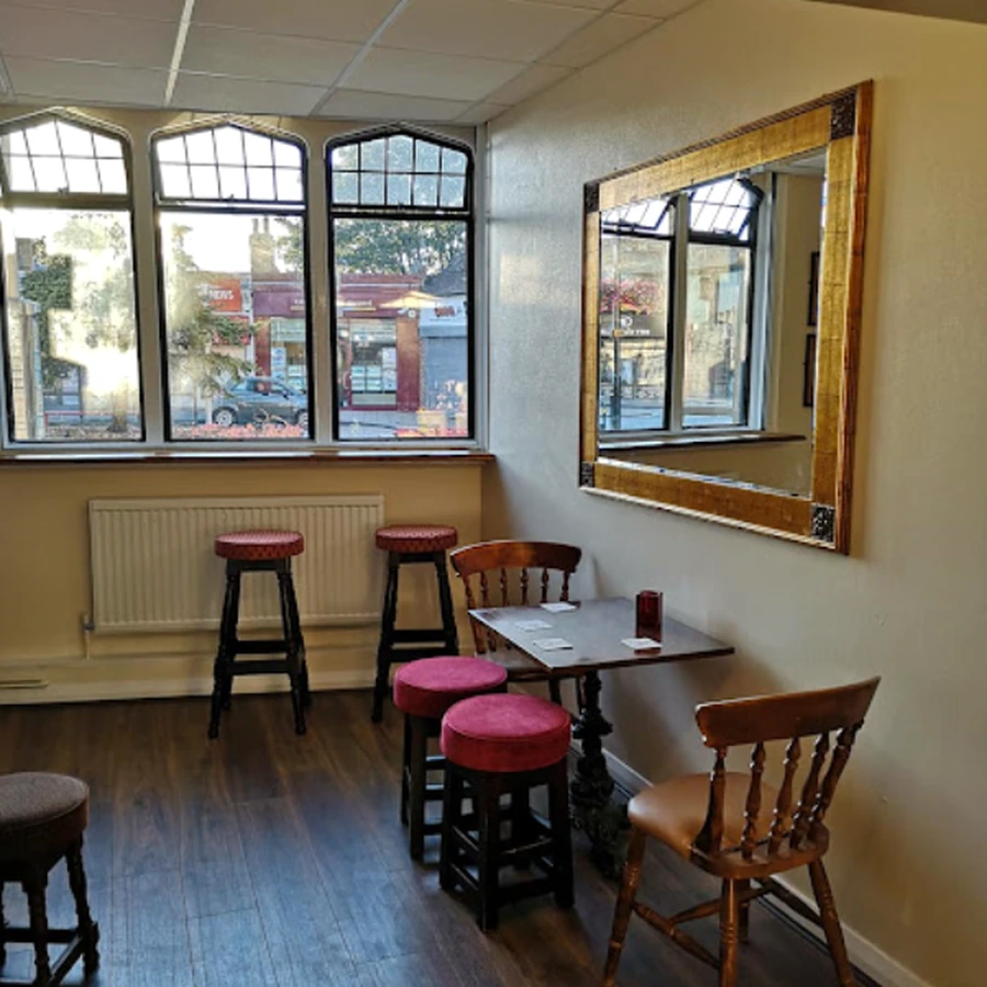 Window seats, wooden chairs and a framed mirror inside the pub